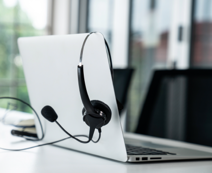 Headset hängend über einem geöffneten Laptop auf einem Konferenztisch