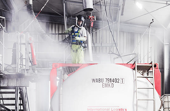 Mann in Arbeitskleidung reinigt einen Container mit Hochfruckreiniger